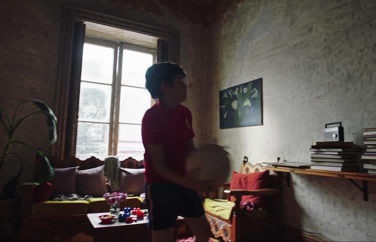 Little boy indoors with a ball throwing against the wall while playing