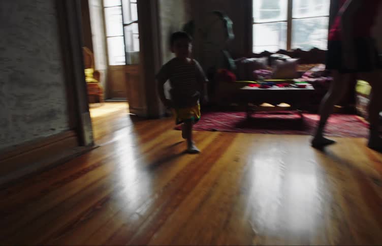 Boy with a soccer ball kicking against the living room wall and a toddler running around the house