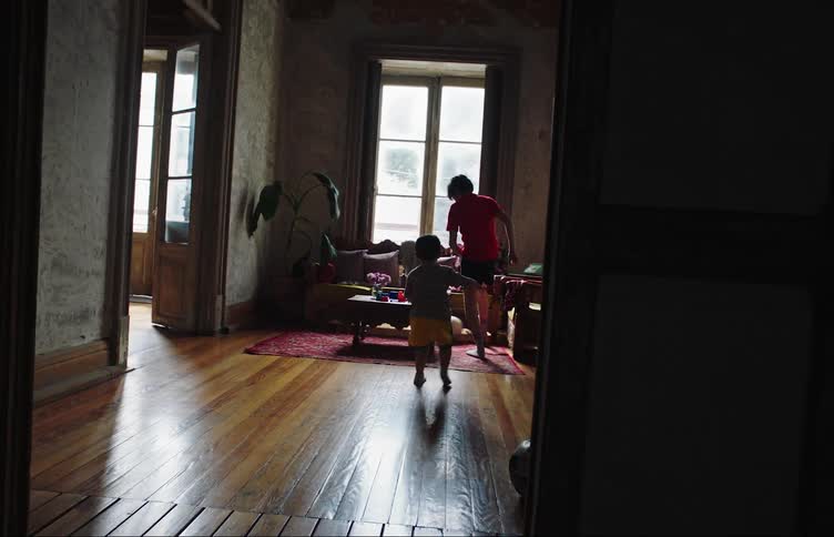 Two children play with a soccer ball in the living room
