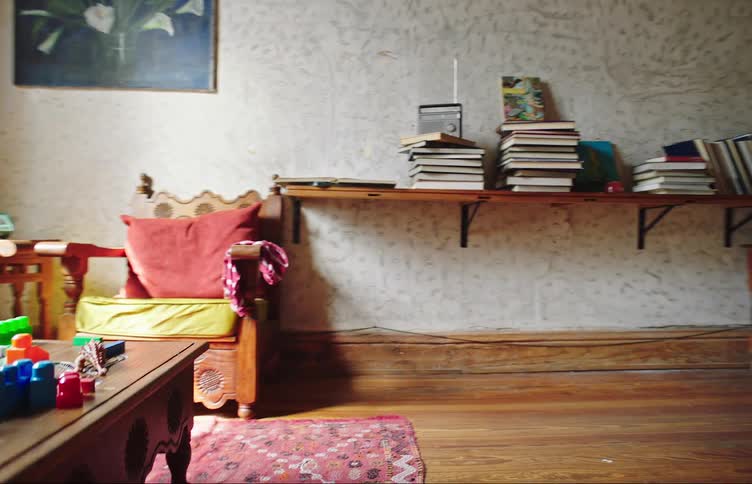 Youth plays with soccer ball inside house while younger brother stands in next room