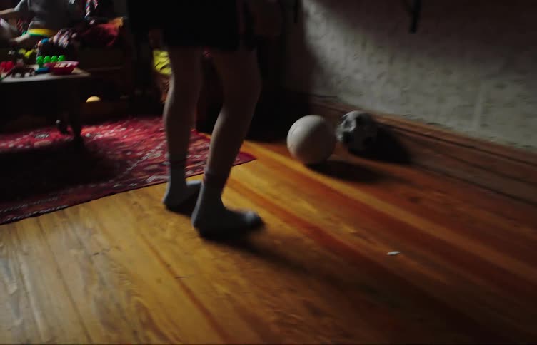 A boy plays soccer inside a home