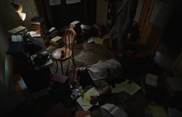 Detectives entering a dimly lit room with a dead man face down on the bloody floor