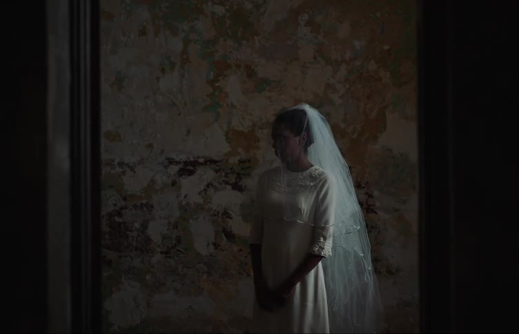 Woman in a room with a veil on her head and a white wedding dress