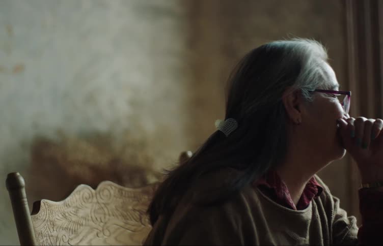 An old woman is talking to someone in front of her and she is wearing prescription glasses