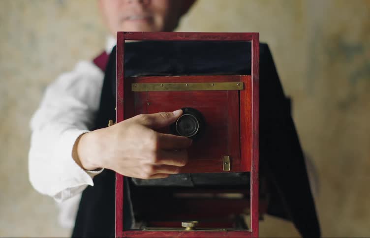 Man adjusting the lens of a vintage camera and preparing to take a photo