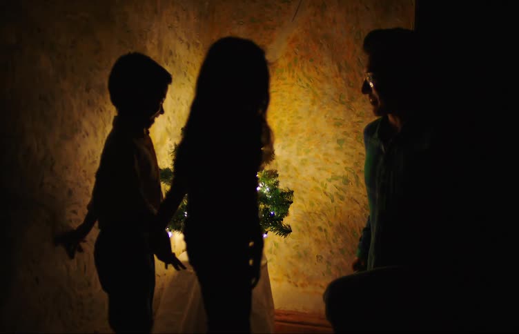 A mother hands two gifts to two children