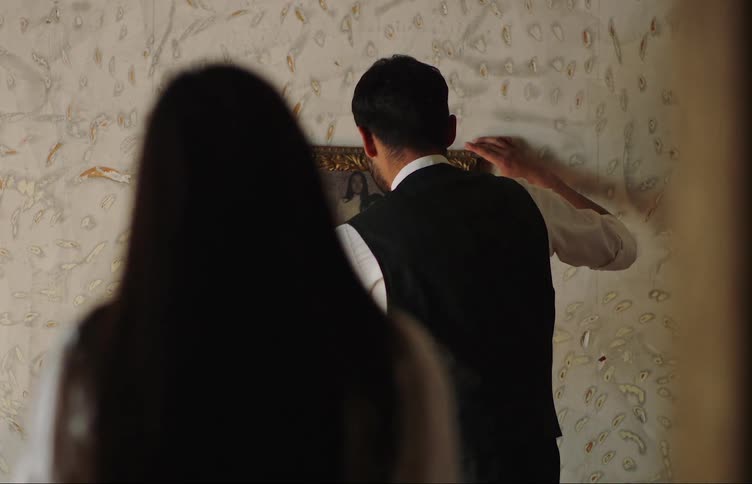 Man adjusting a picture on a wall and a woman helping