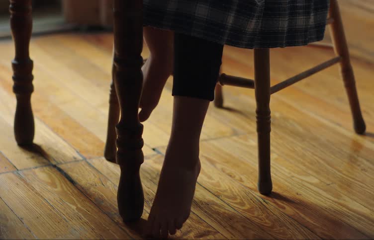 A female dangles her foot while sitting in a chair