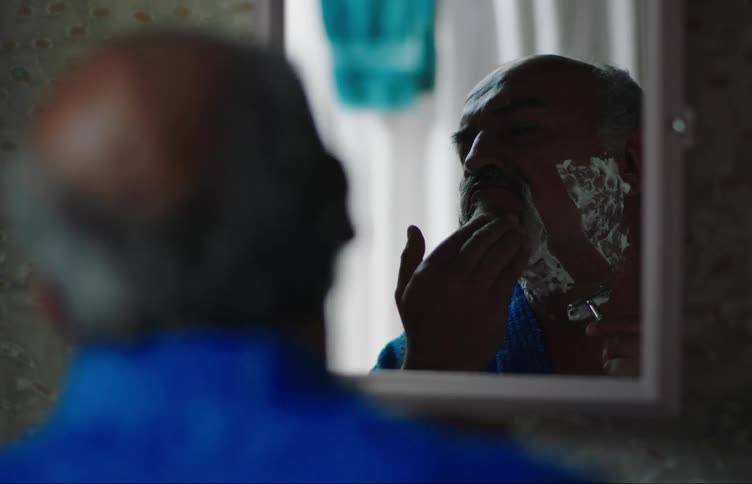 Earthquake makes the room shake as man shaves inmirror and he walks away