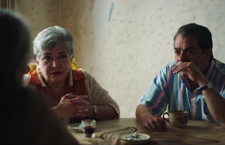 Elderly people sitting at a table with cups of coffee talking to each other