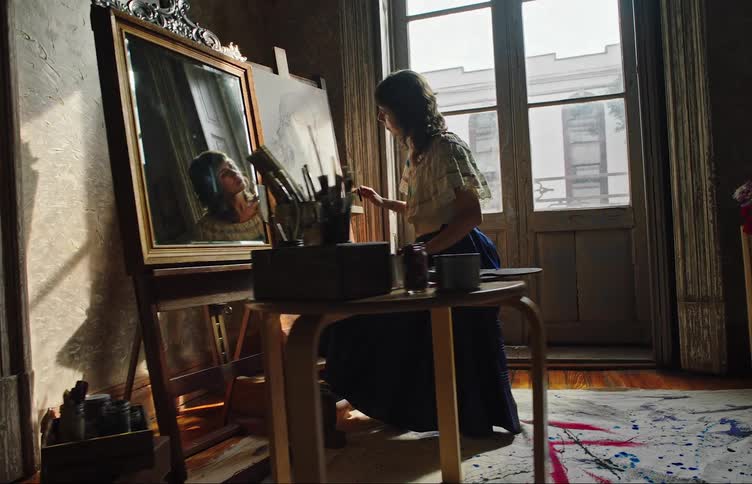 Woman sitting and concentrated while illustrating and drawing a womans face on a white canvas