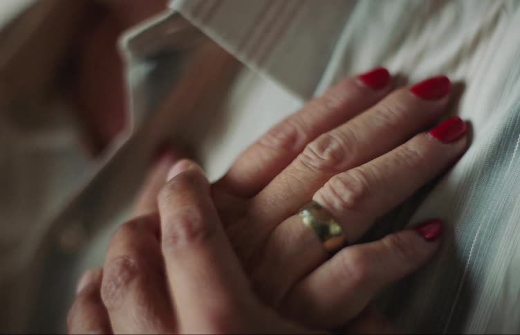 Closeup on a ladys hands placed on the chest of a man holding his hand