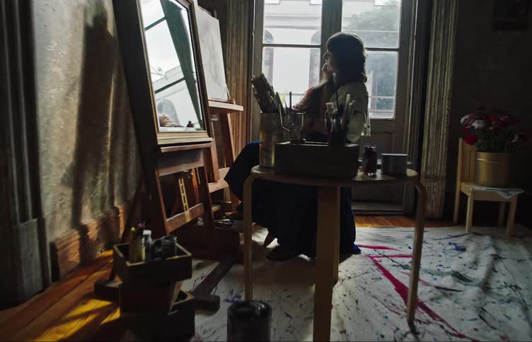A woman is sitting in front of a mirror with a young girl on her lap drawing a self portrait on canvas