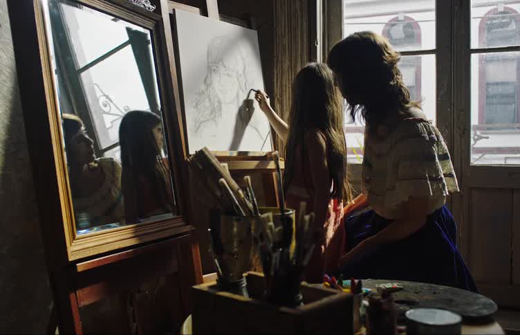 A mother watches her daughter draw on a canvas