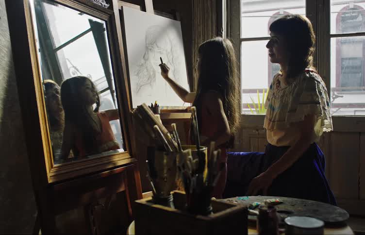 Mother sitting helping her daughter as she draws on a whiteboard in the shape of a womans face