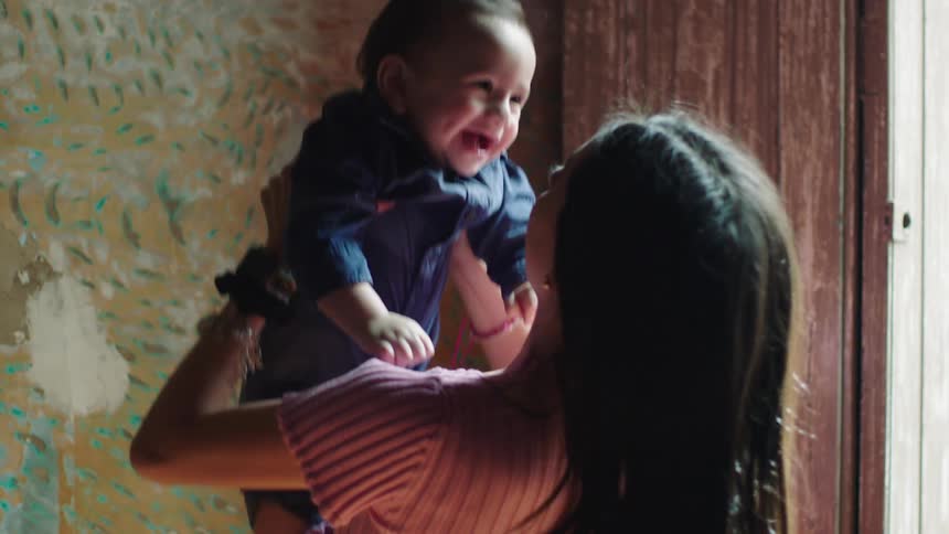 Mother throwing her baby up and holding her with her arms while he gives a beautiful smile