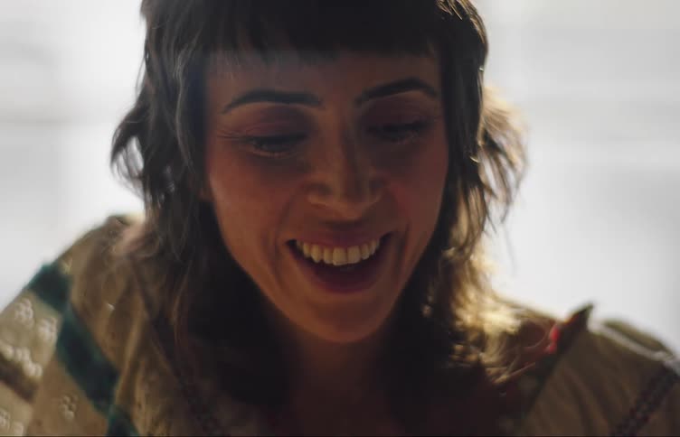 Woman is smiling and talking while standing in a well lit room