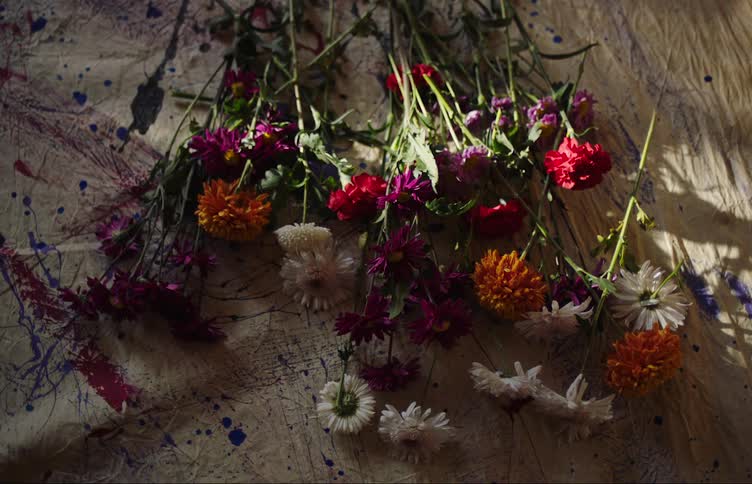 A flower arrangement is laying on the ground atop a paint splattered drop cloth