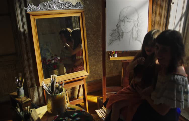 Mother sitting on a chair and her daughter sitting on her lap while both are smiling and happy