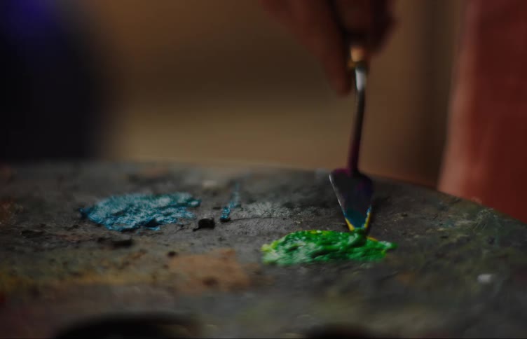 Female painter mixes paints on palette with a palette knife