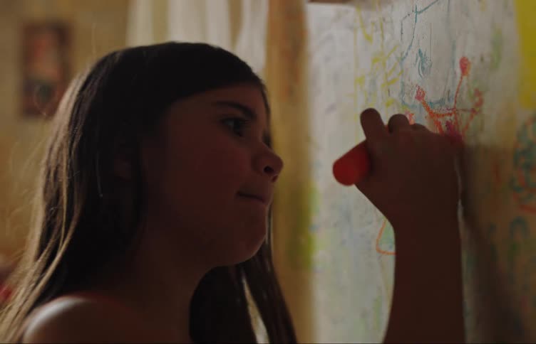 Side portrait of a girl with crayons drawing on a wall