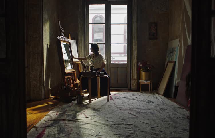 Woman painting a picture in a room and then her little daughter arrives and is picked up by her mother