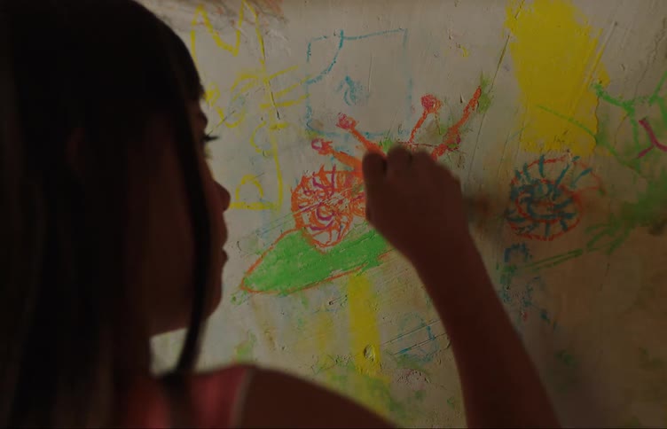 A little girl colors in a bug on a large art piece she is working on