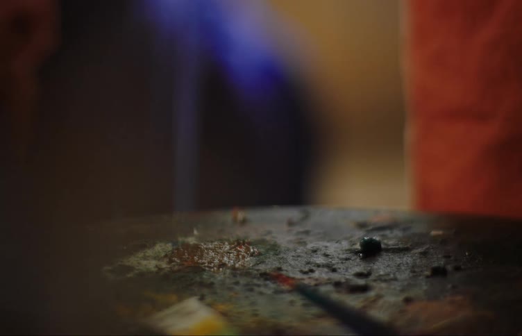 Hands of a woman and a little girl putting paint on a wooden support and stirring in sequence with a spatula