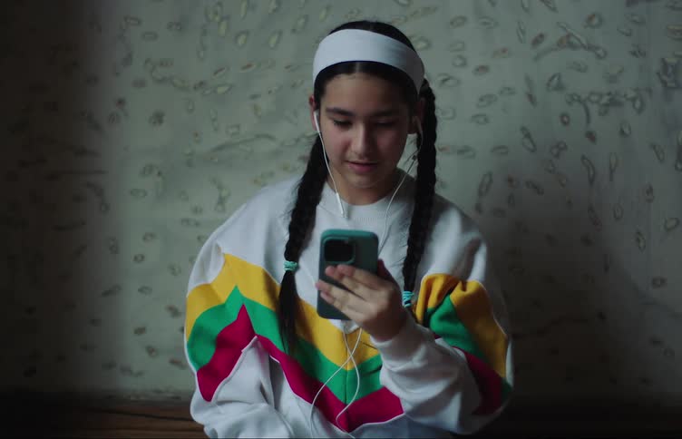 Girl sitting with headphones and talking on her smartphone