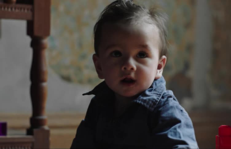 Baby looks around and hits blocks together while sitting on the floor