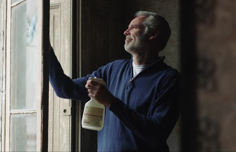 A man sprays the window and cleans it with a rag
