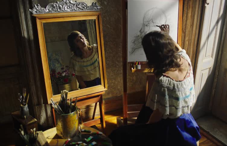 Artist looks at her reflection in mirror while sketching a self portrait