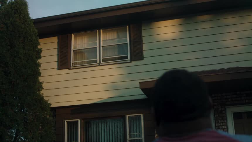 A happy man waving at someone in the window of a house
