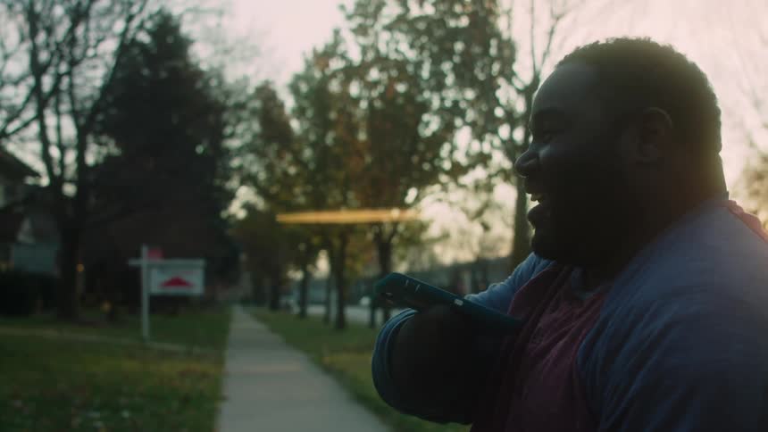 A happy disabled man laughs and waves in a neighborhood at morning
