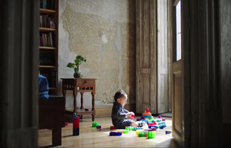 A toddler plays with toys while sitting on the living room floor