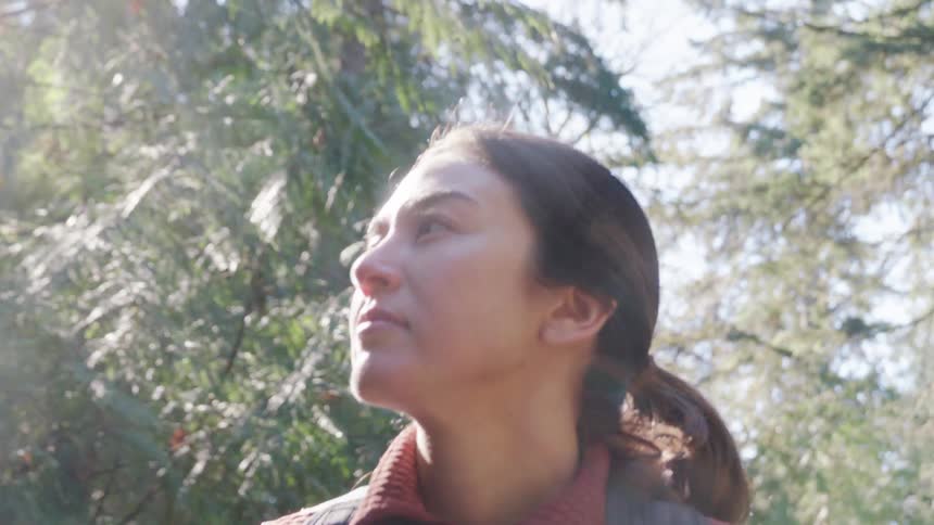 Portrait of a young woman walking through a forest in daylight
