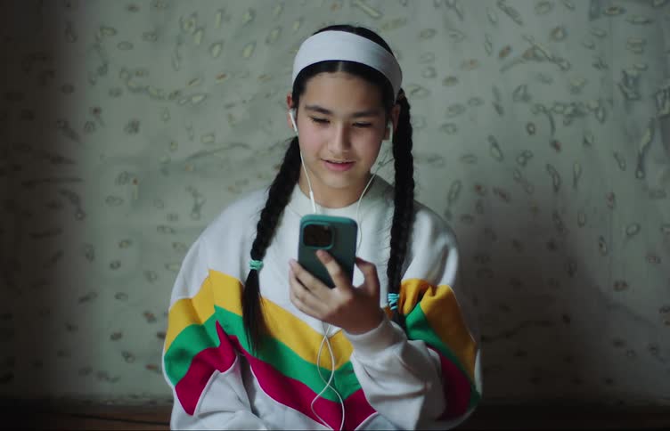 A teenage girl smiles while talking on a smartphone