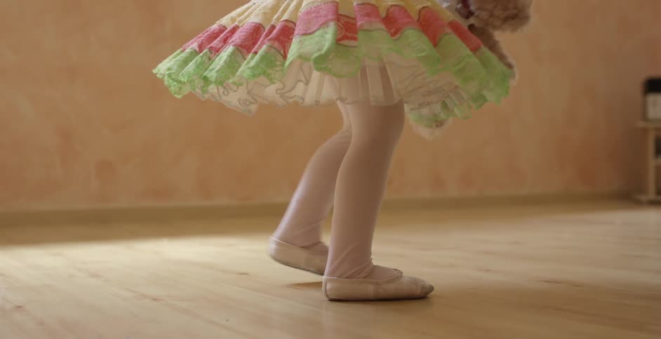 Small girl carrying a teddy bear and swinging it around in her ballet outfit
