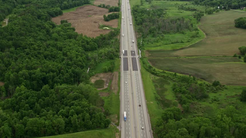 Traffic drives along highway through rural countryside