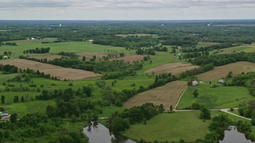 Farms dot the countryside near many trees and a lake