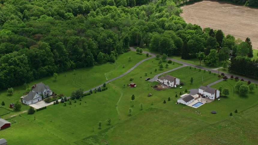 Luxury homes with vast grassy yards next to an empty field and forest