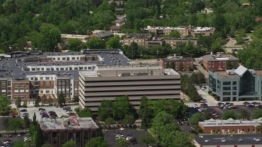 Aerial view of a cityscape with various buildings and parking lots filled with cars