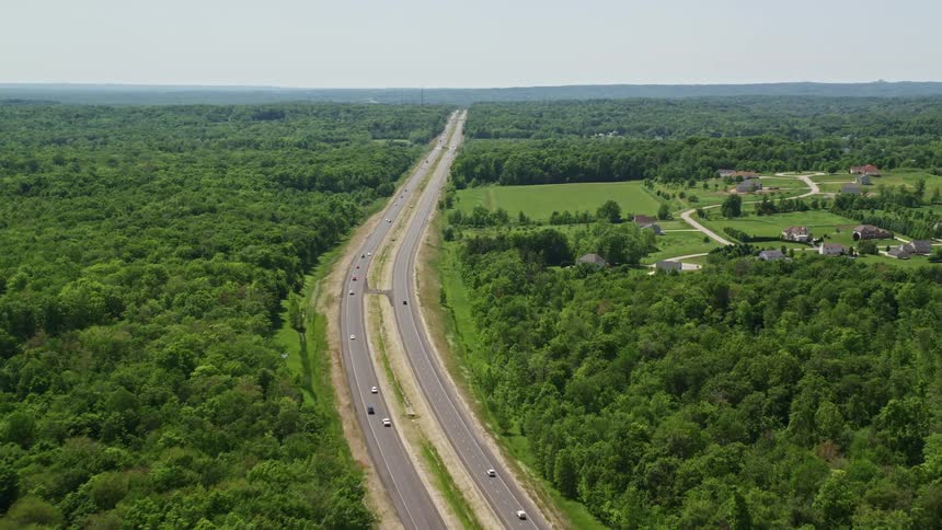 Aerial panorama of an extensive highway with vehicle traffic and rural areas with houses around