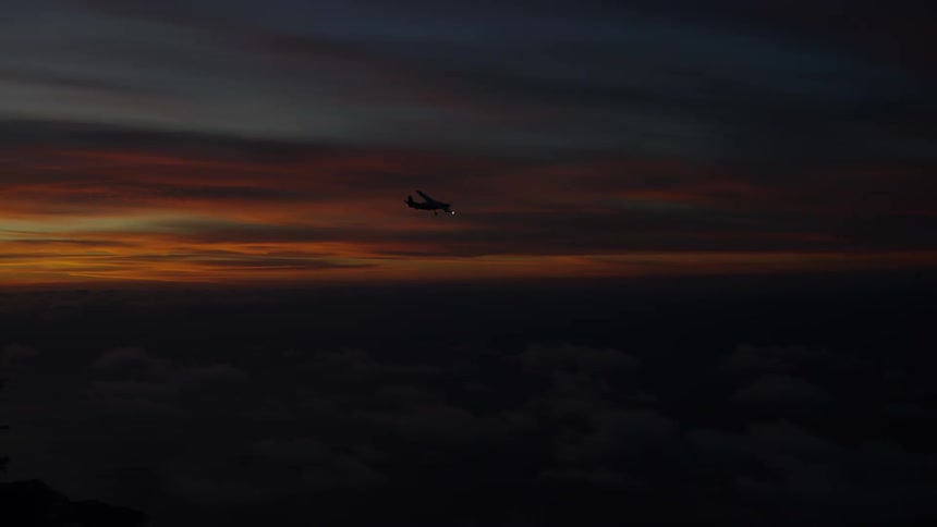 Airplane flying over the dark orange morning sky