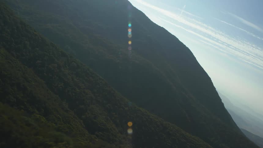 Aerial panorama of mountains covered by forests with sun flare