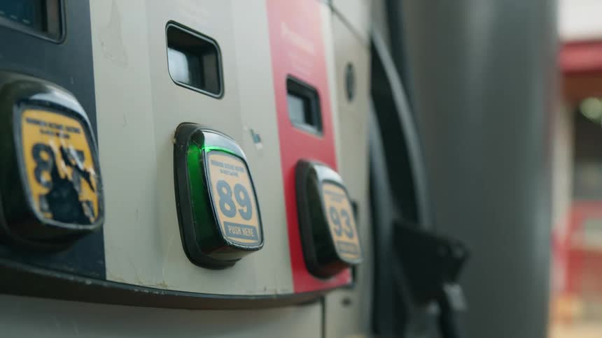 An old woman pushes a button on a gas pump