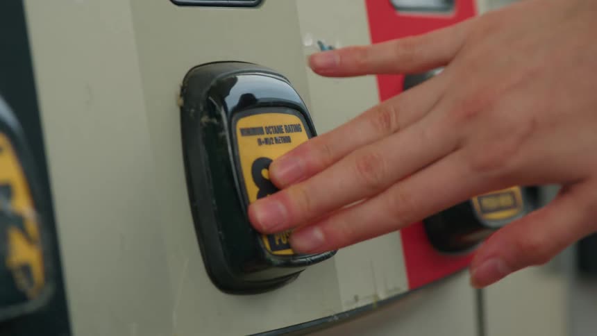 Hand pressing gas octane button at the gas station