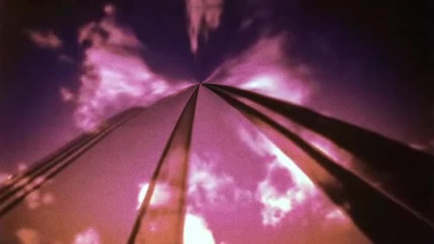 Upwards film footage of a tall skyscraper in a city