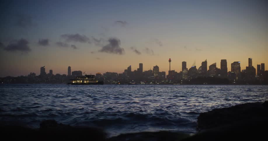Landscape of an ocean with calm waters and in the background the silhouette of a ship and a metropolis with a skyscraper at dusk