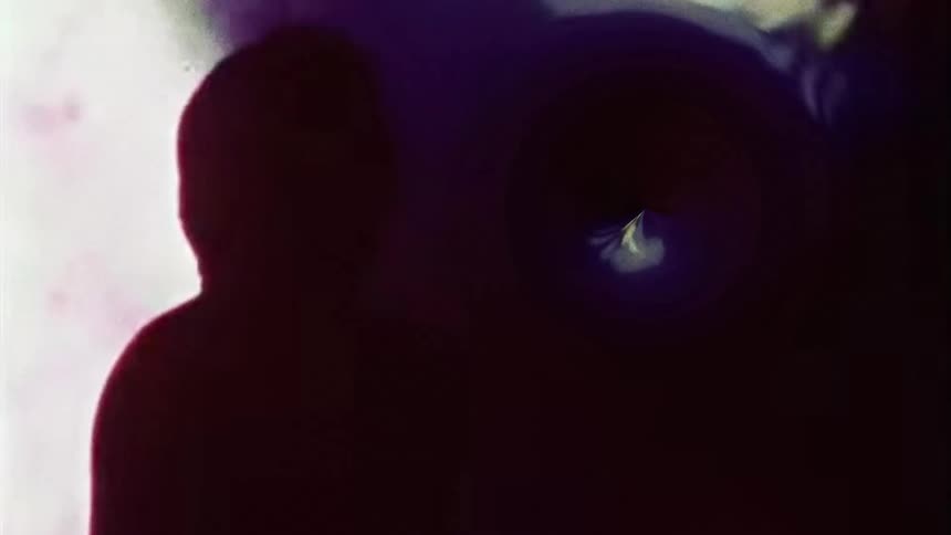 A silhouette of a person who was looking at a colorful hole in the wall and is moving